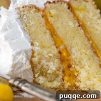 Close up of a bitten into slice of gluten-free coconut lemon cake on a wooden plate, emphasizing its delicious layers.