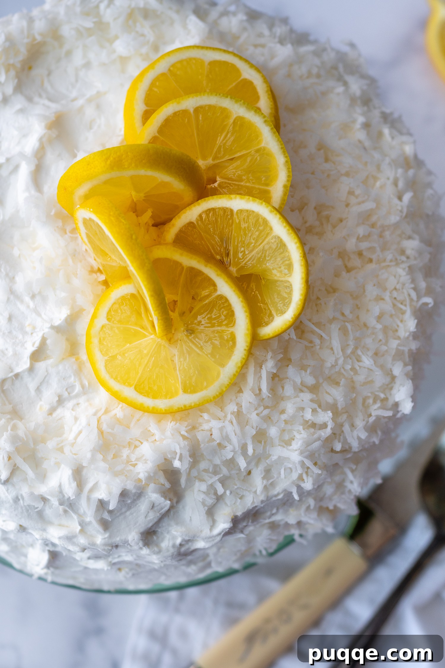 Decadently Moist Gluten-Free Coconut Lemon Curd Velvet Cake 9 Top-down view of the beautifully decorated gluten-free coconut lemon cake, adorned with sweetened shredded coconut and fresh lemon slices.