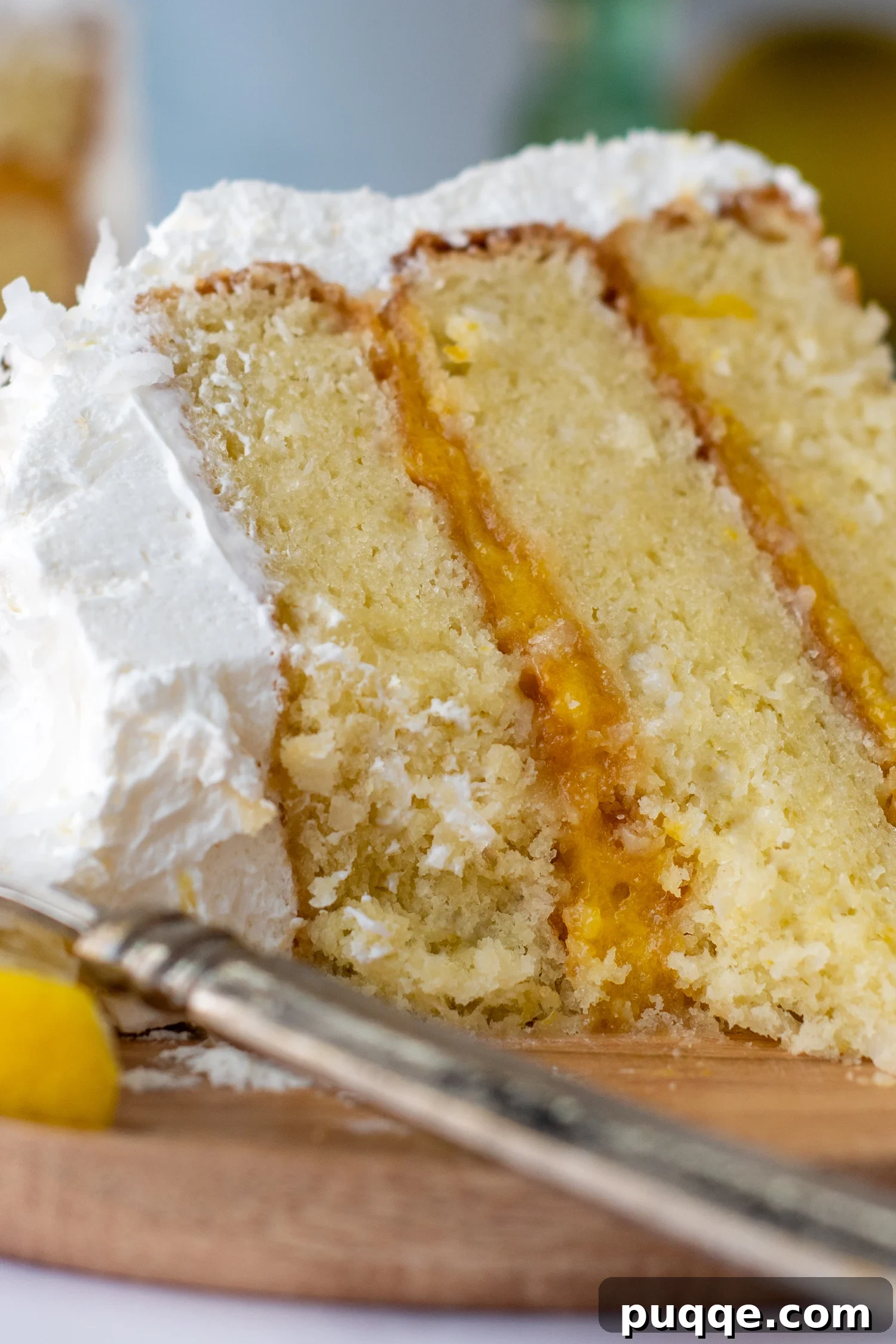 Decadently Moist Gluten-Free Coconut Lemon Curd Velvet Cake 10 Close-up of a delectable bitten slice of gluten-free coconut lemon cake on a rustic wooden plate, showing its intricate layers and textures.