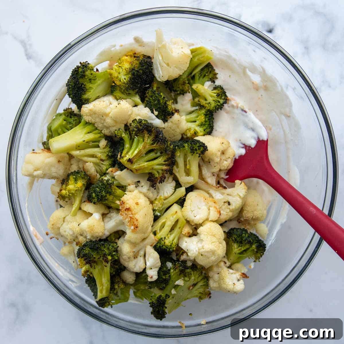 Tender roasted broccoli and cauliflower florets generously coated in the creamy cheese sauce, ready to be transferred to a baking dish.