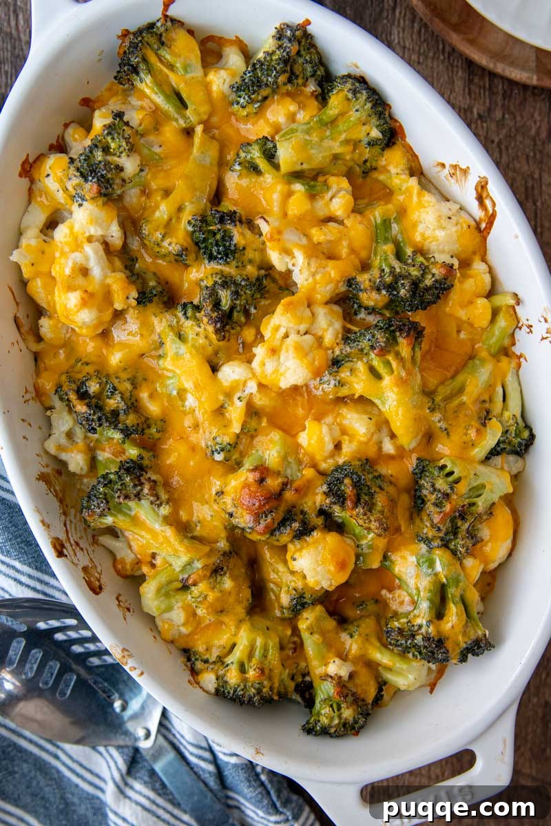 Overhead shot of a beautifully golden, bubbly vegetable casserole featuring broccoli and cauliflower in a white oval baking dish, fresh from the oven.