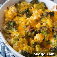 Close-up of melted cheese on broccoli and cauliflower in a casserole dish, highlighting the golden, bubbly texture of the finished dish.