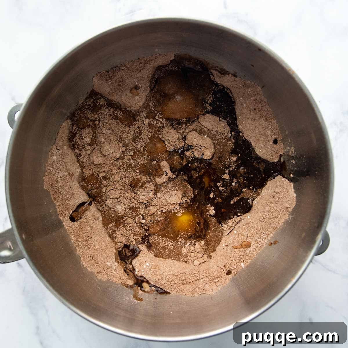 Decadently Moist & Easy Gluten-Free Chocolate Cake 3 Adding eggs and oil to the dry ingredients in a mixing bowl for gluten-free chocolate cake.