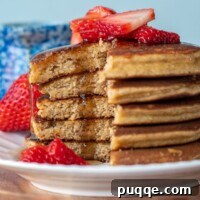 a stack of pancakes made with almond flour that are cut and syrup drizzling down