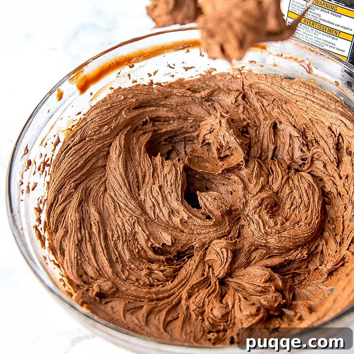 whipped chocolate ganache frosting in a glass mixing bowl.