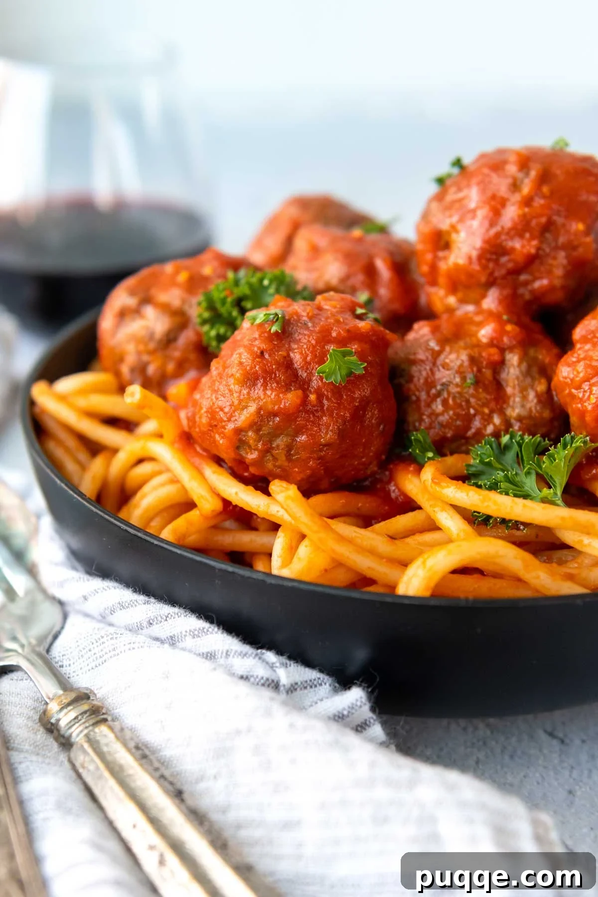 Juicy meatballs served generously over gluten-free pasta in a sleek black bowl.