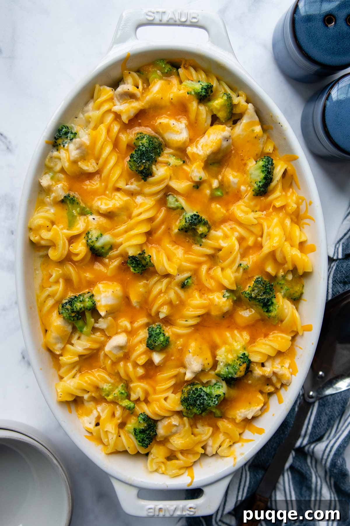 Overhead shot of a comforting chicken and broccoli pasta casserole with melted cheddar cheese on top.