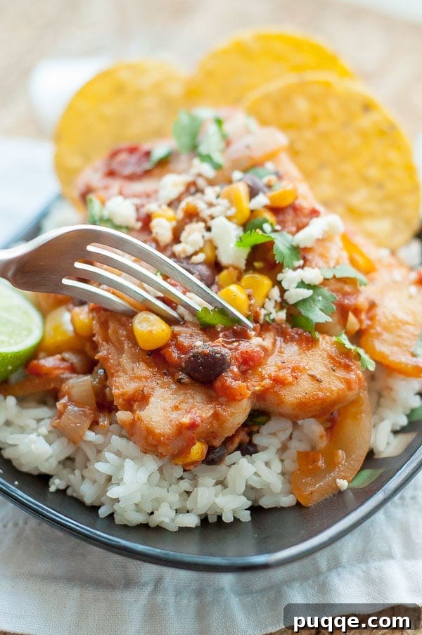 A fork poised to cut into a plate of vibrant Mexican fish, served over a bed of rice.
