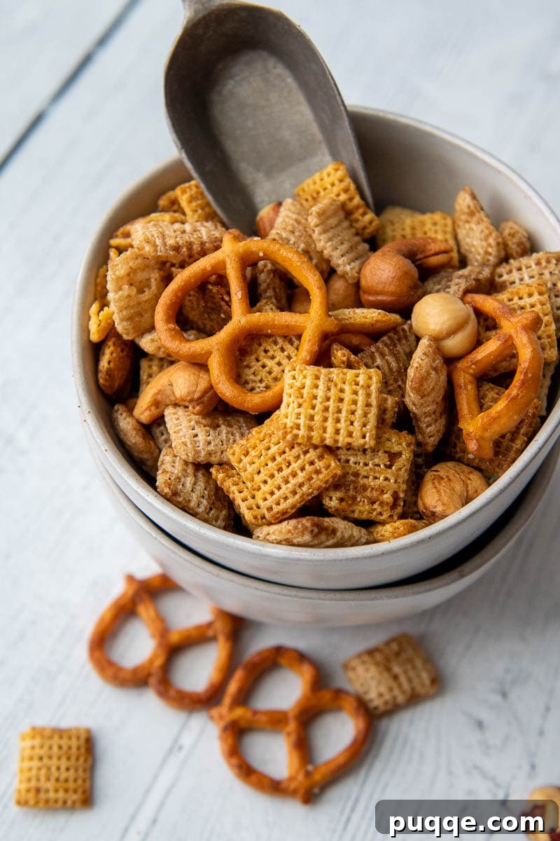 A small bowl of bold and zesty gluten-free snack mix with a small scoop inside.