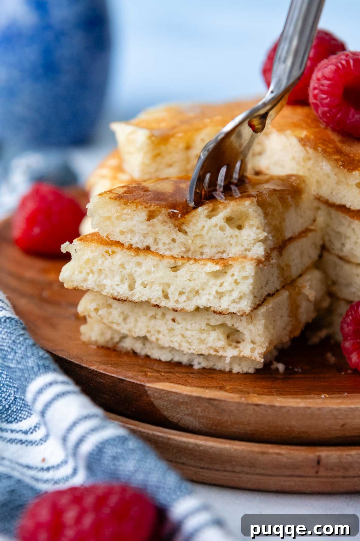 A fork piercing a stack of fluffy gluten-free pancakes, with a bite removed.