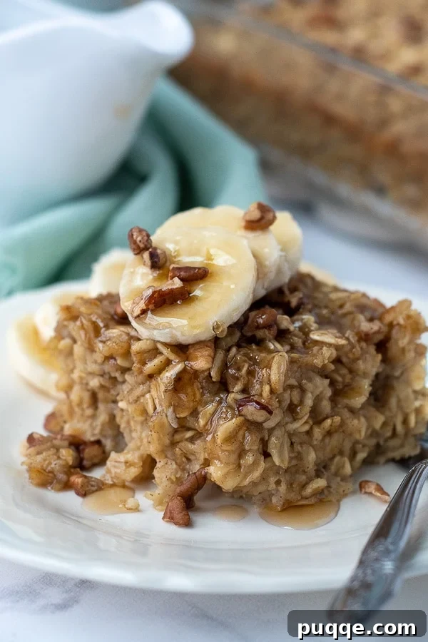 A slice of warm banana baked oatmeal with maple syrup gracefully dripping off.