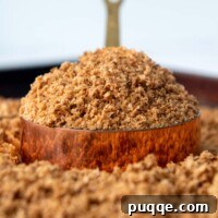a heaping scoop of bread crumbs in a copper measuring cup