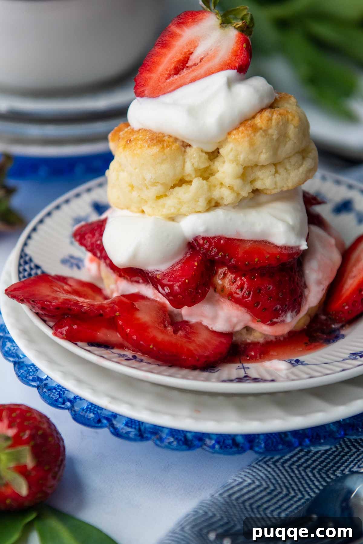 A perfectly assembled gluten-free strawberry shortcake, with a golden biscuit base, vibrant strawberries, and a generous dollop of whipped cream, set against a backdrop of fresh berries.