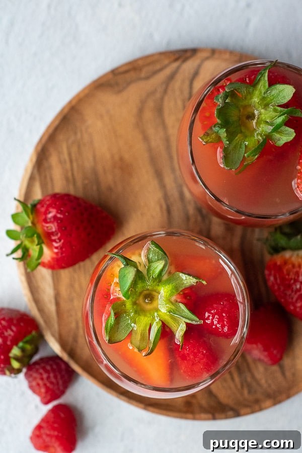 Rosé Bloom Sangria 3 Overhead shot of summer berry sangria glasses with fresh strawberries and raspberries sticking out of the glasses, garnished elegantly.