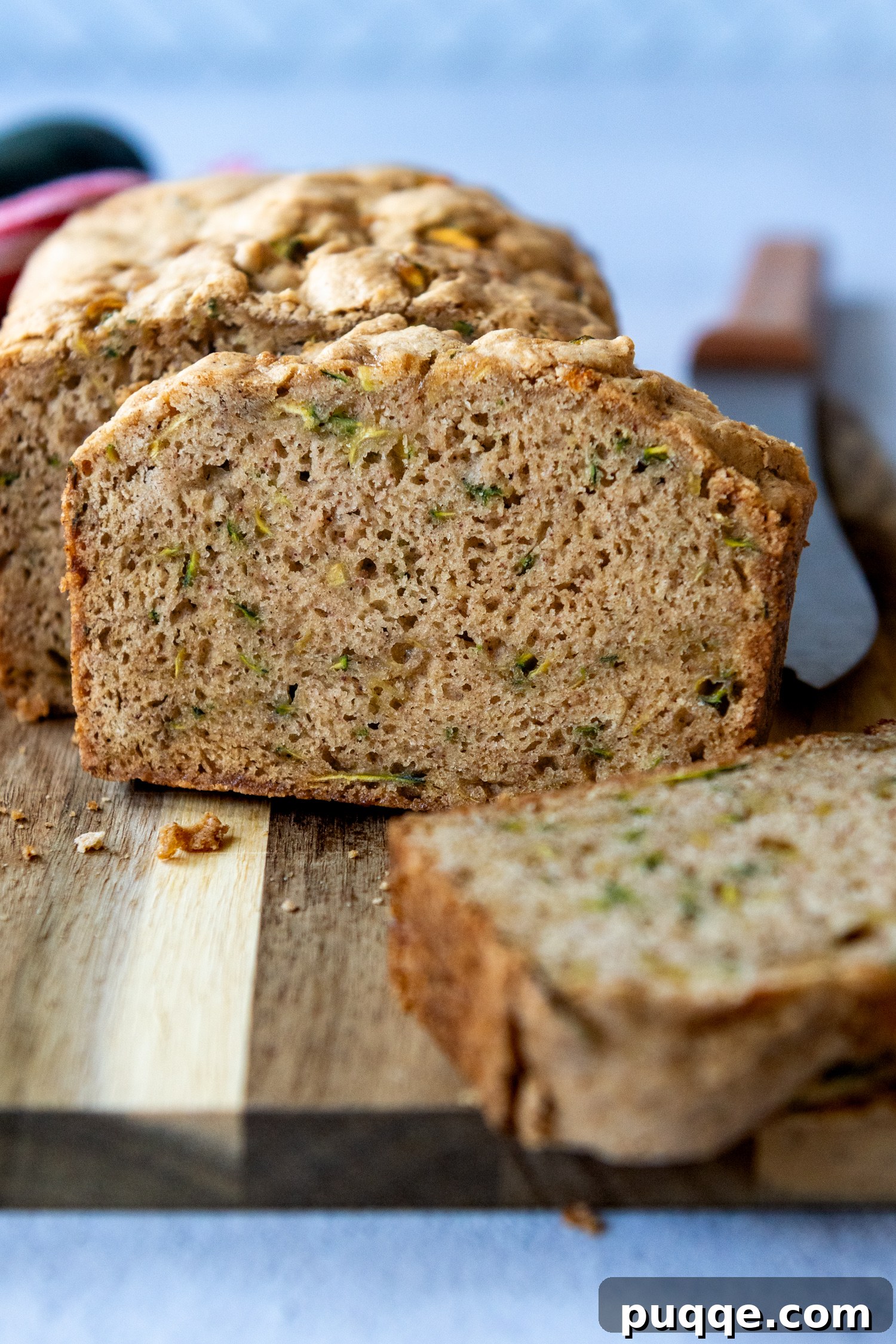 Seriously The Best Gluten Free Zucchini Bread Incredibly Moist 2 A perfectly baked slice of gluten-free zucchini bread, showcasing its moist texture and golden-brown crust, resting on a wooden cutting board.