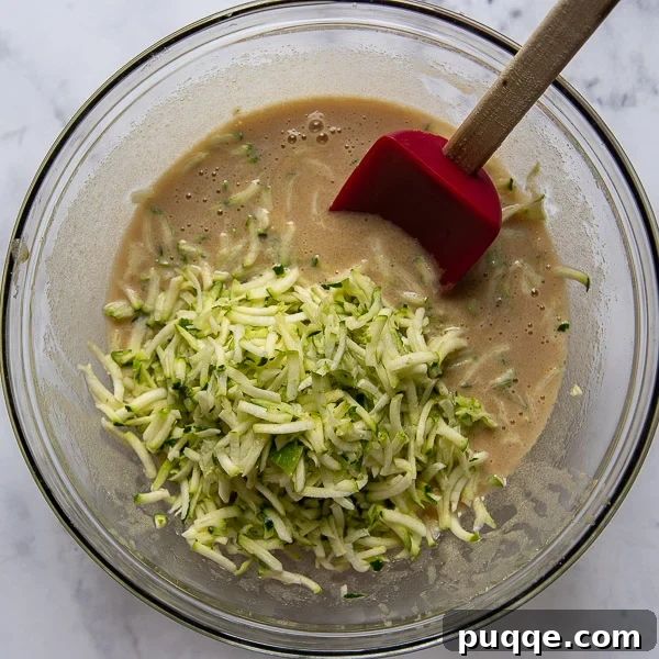 Seriously The Best Gluten Free Zucchini Bread Incredibly Moist 4 Wet ingredients including sugar, oil, egg, and vanilla being whisked together in a bowl.