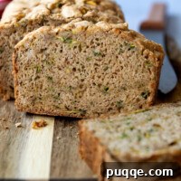 A slice of gluten-free zucchini bread on a wooden cutting board, ready to be served.