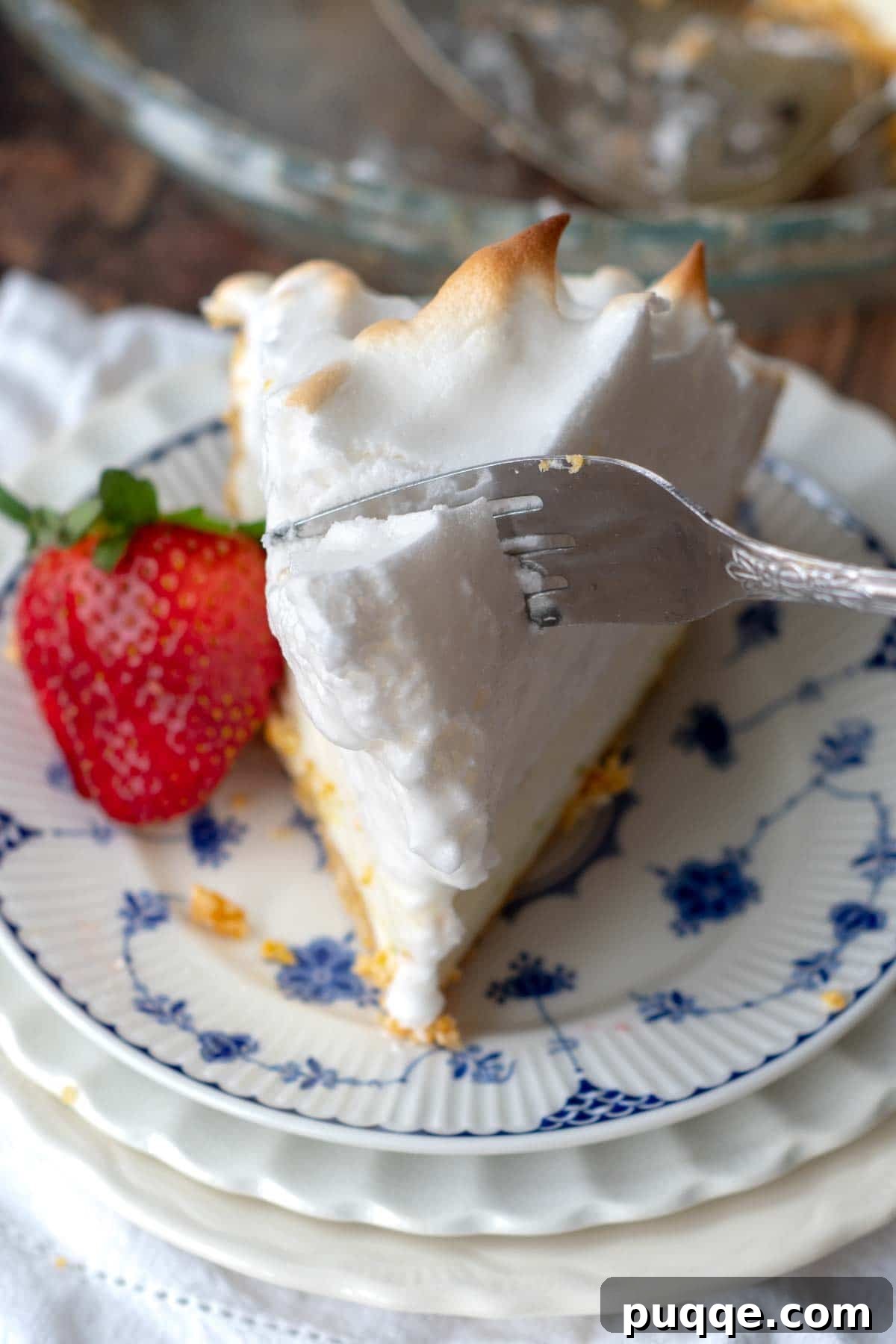 Zesty Frozen Lemon Bliss 4 A fork gently piercing into the perfectly toasted meringue topping of a creamy frozen lemon pie, highlighting its fluffy texture.