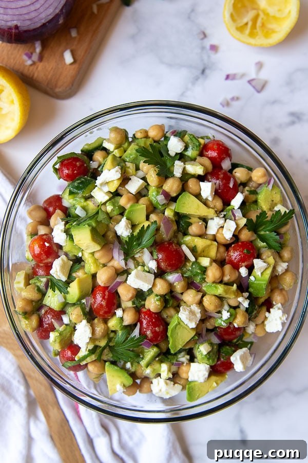 Creamy Avocado Chickpea Salad 4 Overhead shot of a vibrant Mediterranean Chickpea Avocado Salad, generously filled with whole grape tomatoes, sliced cucumbers, and creamy avocado chunks in a large serving bowl.