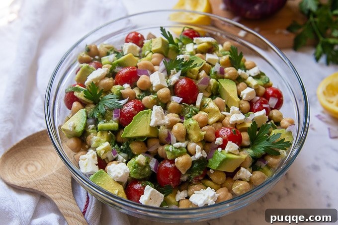Creamy Avocado Chickpea Salad 5 A beautifully arranged large serving bowl of Mediterranean Chickpea Avocado Salad, ready to be enjoyed, with a wooden serving utensil resting beside it.