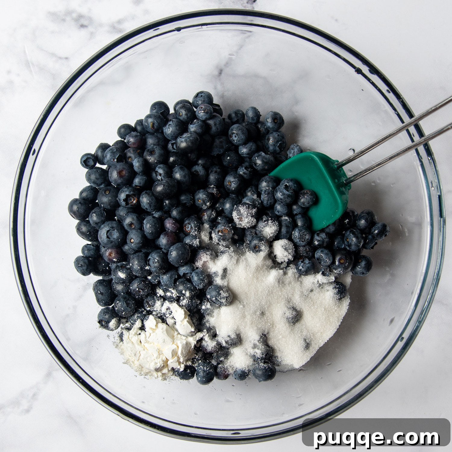 berries in a large glass bowl with sugar and cornstarch.