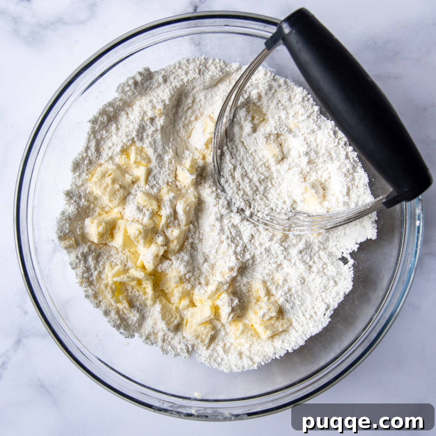 the butter being mixed into the dry ingredients with a pastry blender.