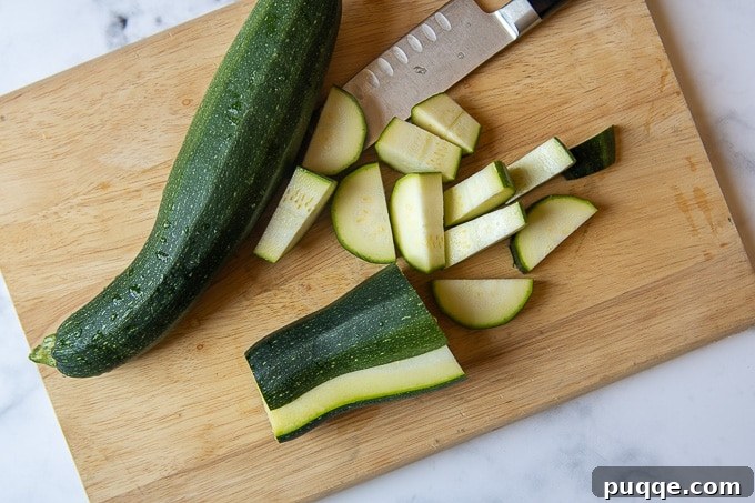 Bright Lemon Garlic Zucchini 3 an image showing fresh zucchini being expertly cut into uniform semi-circles on a rustic wooden cutting board, ready for sautéing.
