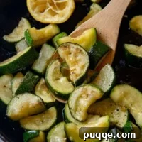 Bright Lemon Garlic Zucchini 5 close up shot of cooked zucchini being held by a wooden spoon