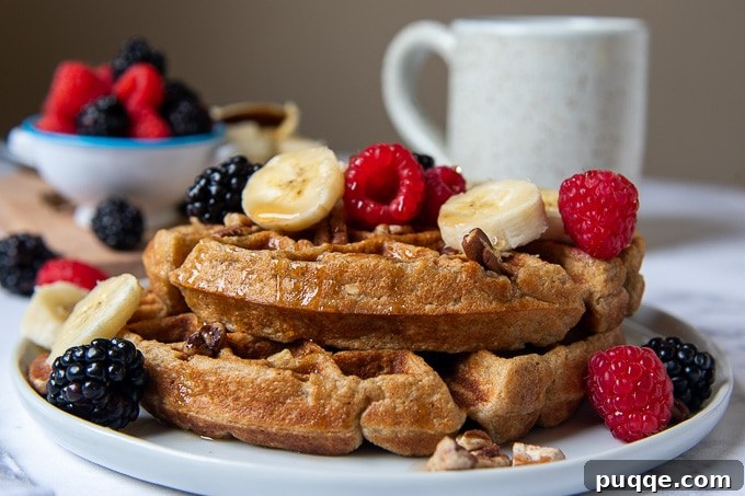 Wholesome Fluffy Gluten Free Banana Oatmeal Waffles 5 close up of a stack of 2 waffles with sliced bananas and berries on top