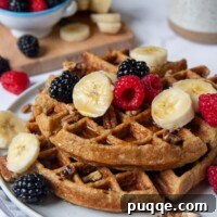 Wholesome Fluffy Gluten Free Banana Oatmeal Waffles 6 shot of gluten free waffles on a plate with berries, nuts, and bananas on top