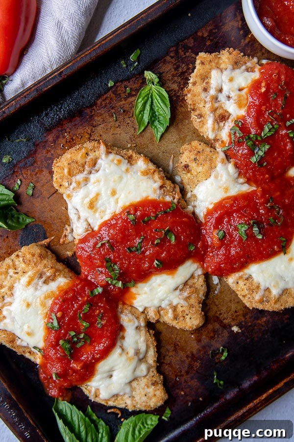 Oven-Crisp Gluten-Free Chicken Parmesan 2 overhead shot of a baking sheet of gluten free chicken parmesan with fresh basil scattered around