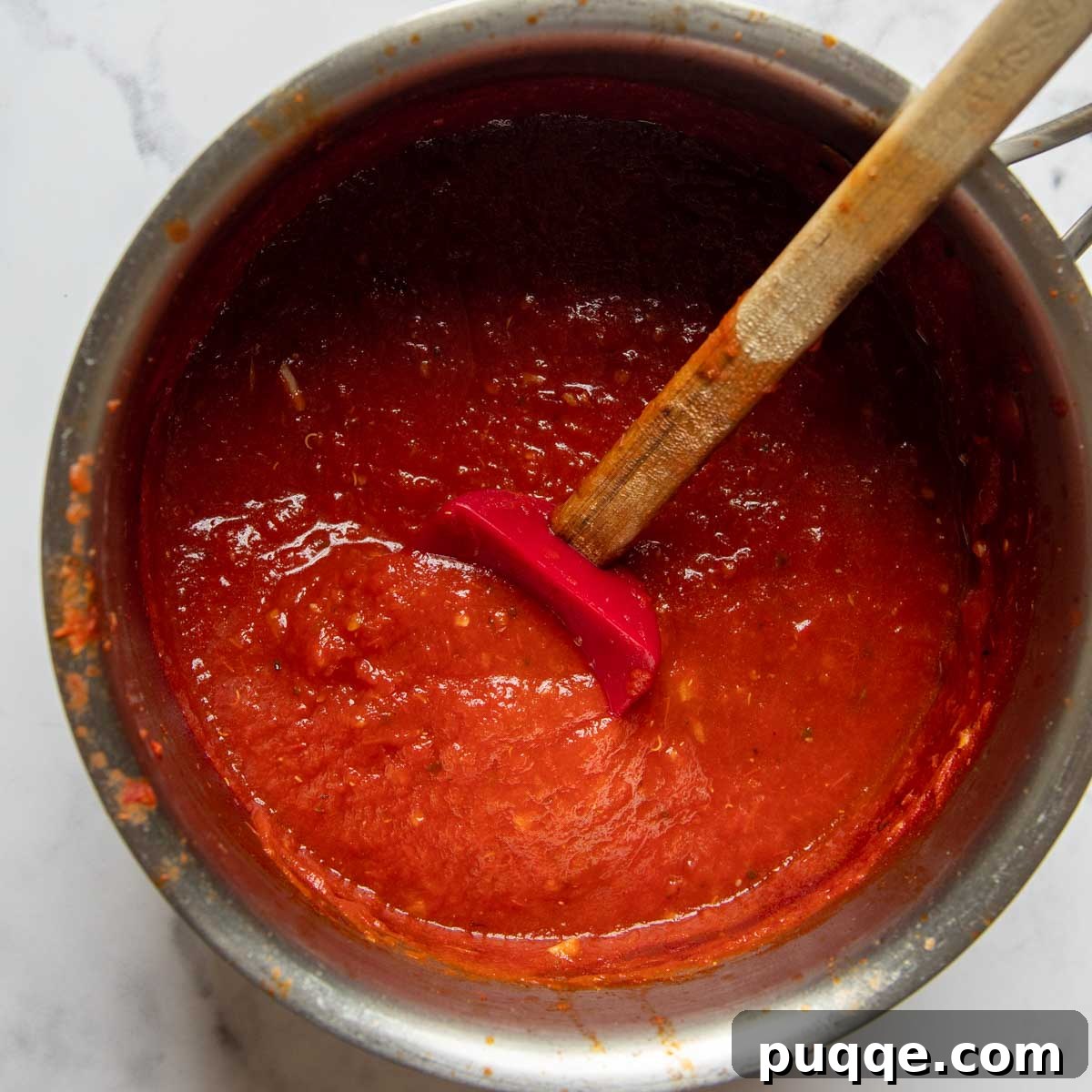 Oven-Crisp Gluten-Free Chicken Parmesan 3 marinara sauce in a pot being stirred.