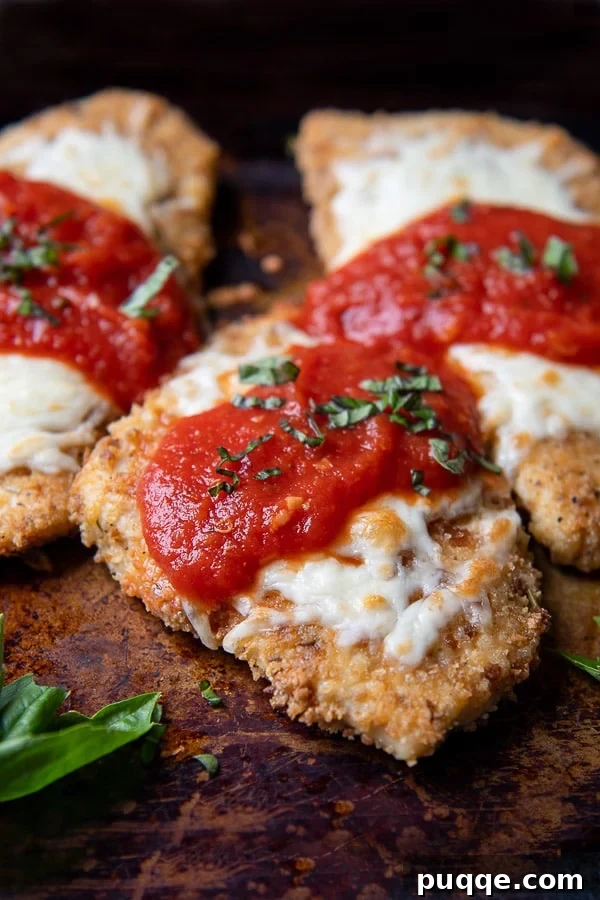 Oven-Crisp Gluten-Free Chicken Parmesan 7 a close up of parmesan chicken on a baking sheet with sauce and cheese on top