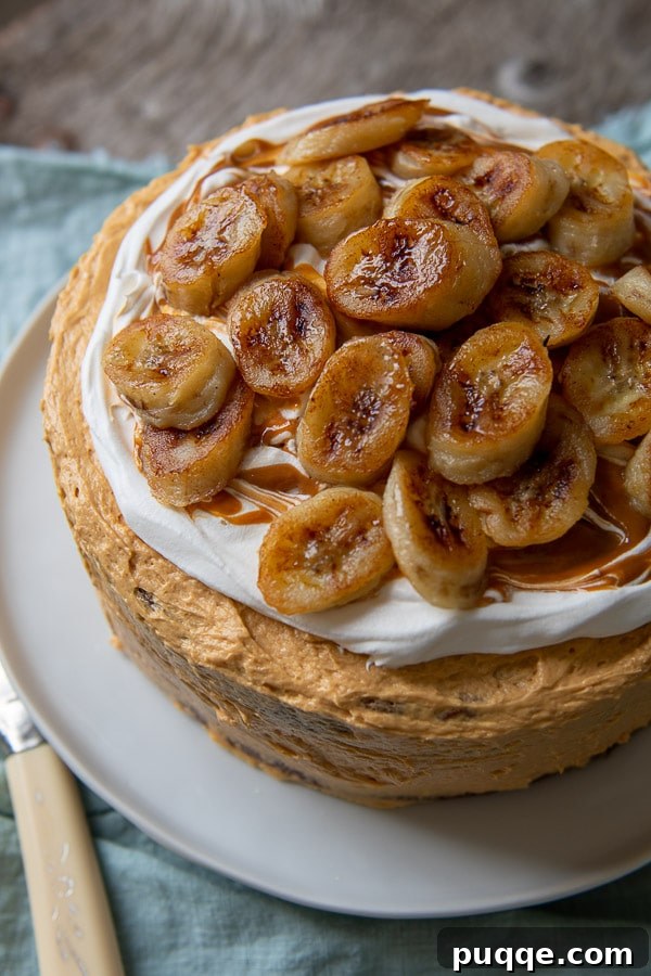 Decadent Banoffee Cake 2 overhead shot of banoffee cake with sauteed bananas on top, featuring golden brown, caramelized banana slices beautifully arranged on a creamy dulce de leche frosting, atop layers of moist banana cake.