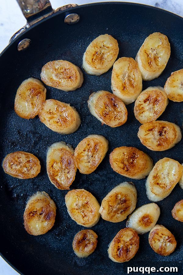 Decadent Banoffee Cake 8 overhead shot of pan fried bananas in a saute pan, showing golden brown, caramelized banana slices ready to be removed from the heat.