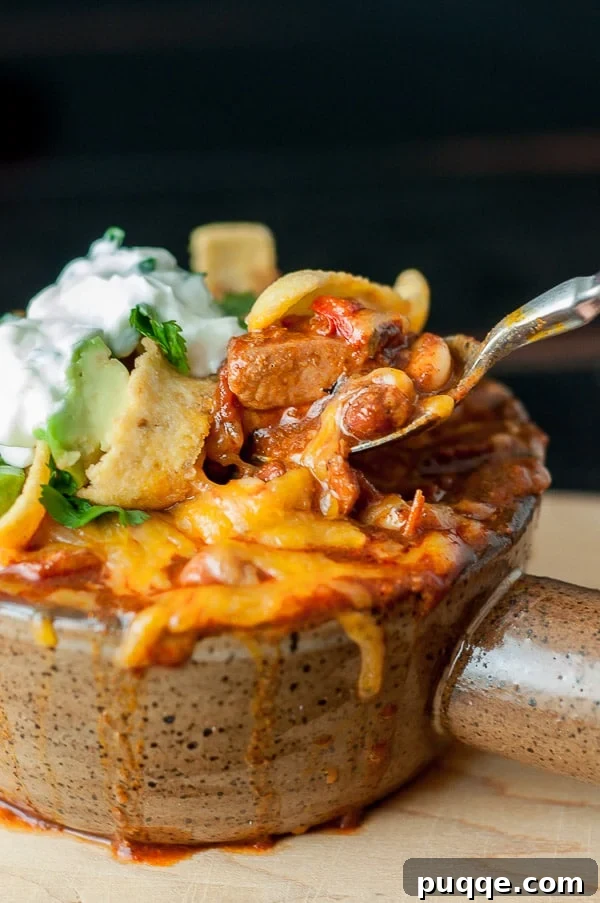 Signature Red Chicken Chorizo Chili 2 A close-up of a spoon taking out a bite of chicken chorizo chili topped with melted cheese.