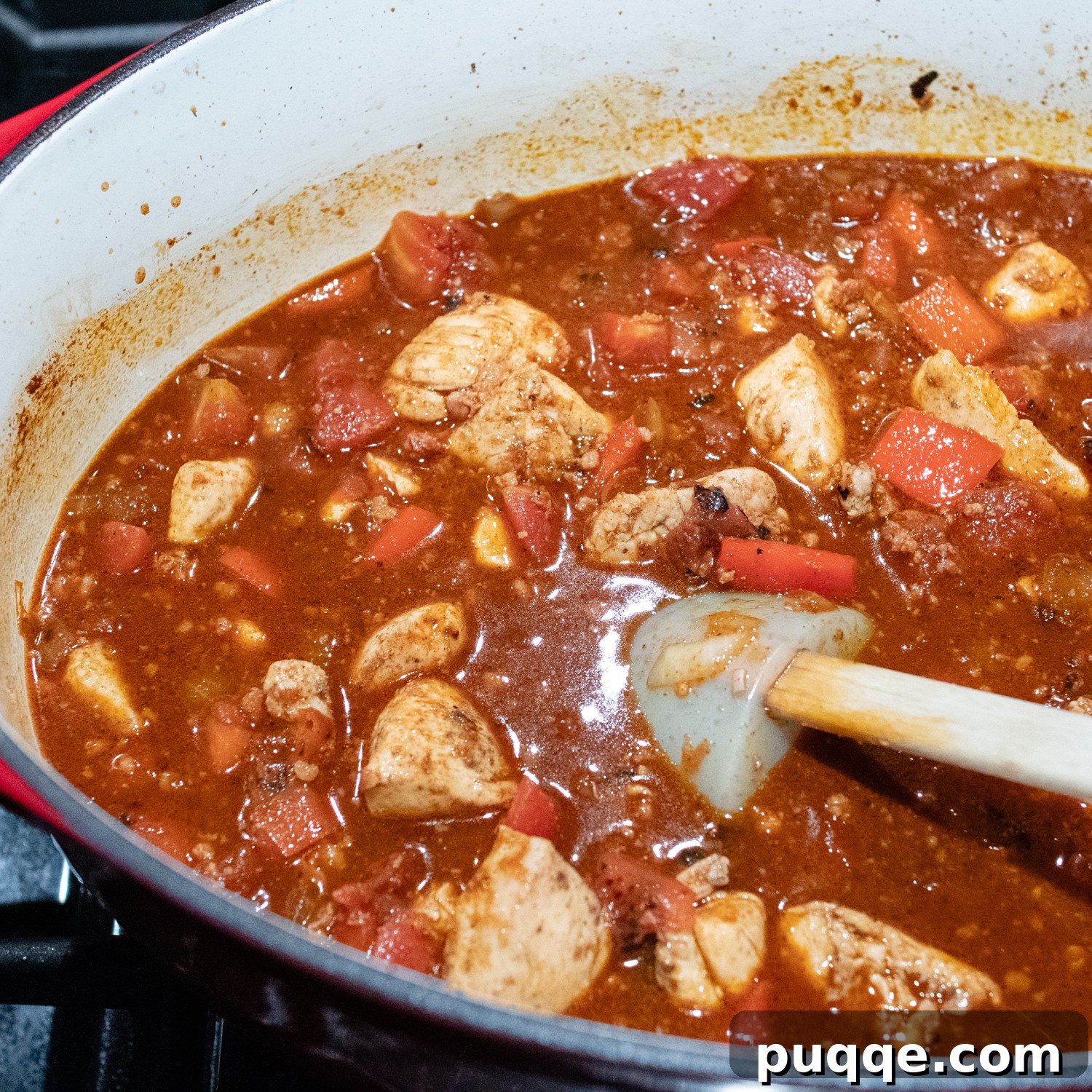 Signature Red Chicken Chorizo Chili 7 The red sauce being added to the chicken and other ingredients for simmering.