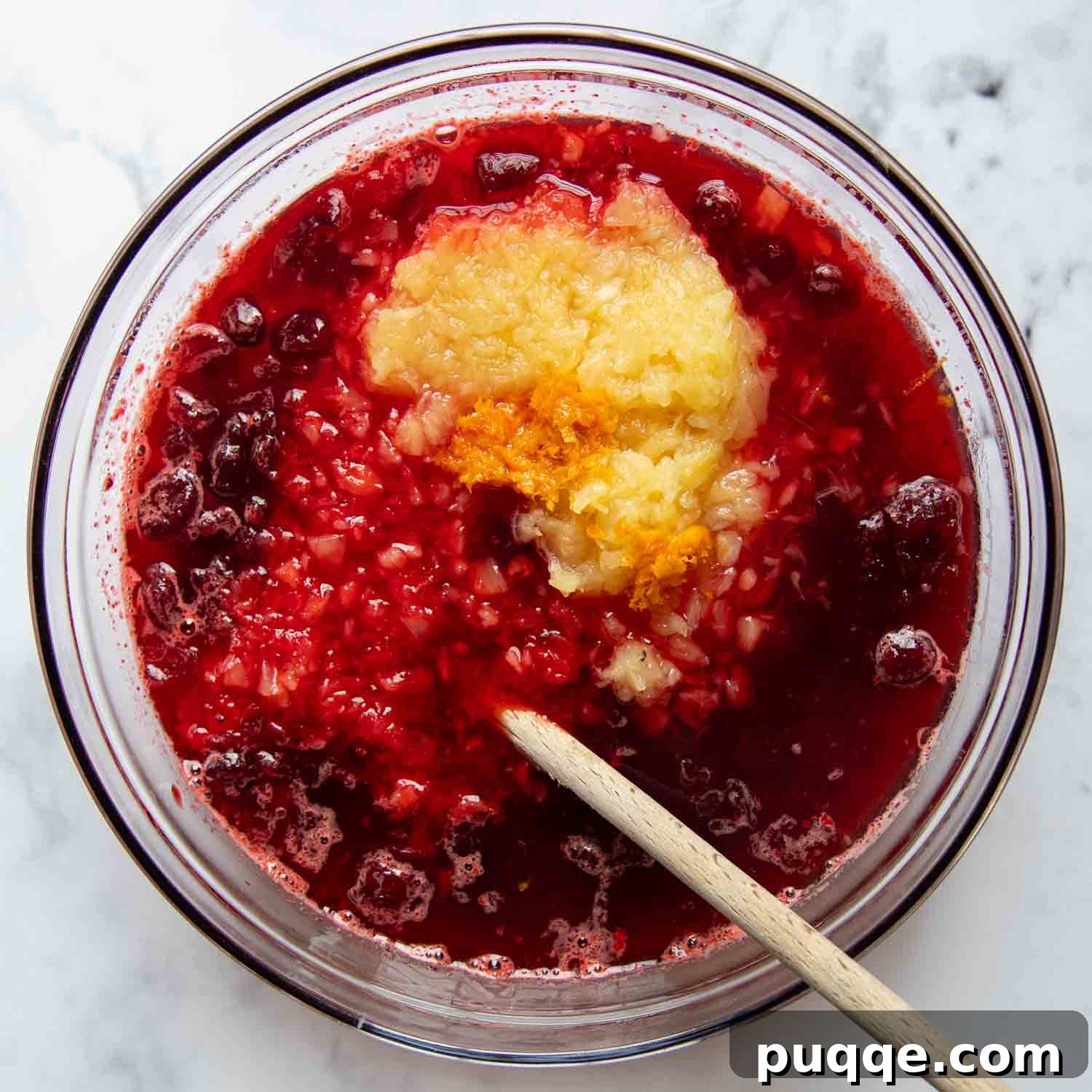 Classic Cranberry Raspberry Gelatin Mold 3 Dissolved jello with cranberry sauce and crushed pineapple in a large glass bowl, ready for chilling.