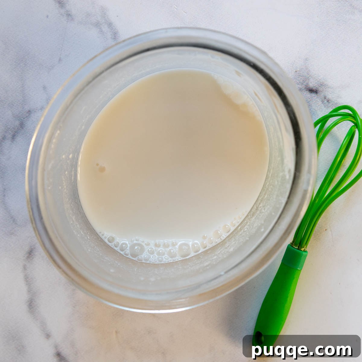 liquid ingredients in a small glass bowl with a whisk next to it.