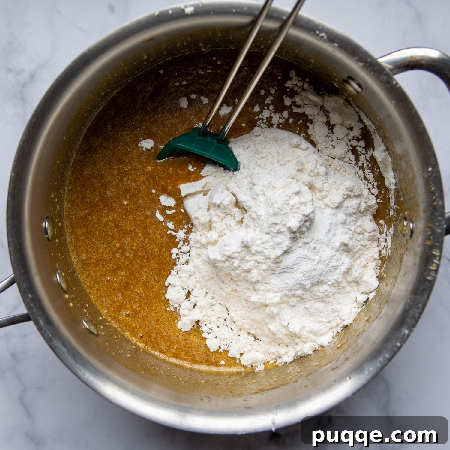Legendary Fluffy Gluten-Free Pumpkin Bread 5 A large saucepan contains the thick pumpkin bread batter, being mixed with gluten-free flour, baking powder, and baking soda until fully combined, showing a rich, smooth consistency.