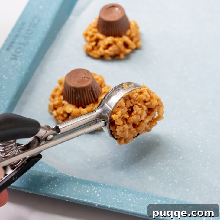 Ghoulishly Easy No-Bake Spider Treats 5 A cookie scoop precisely portioning out the warm crispy rice cookie mixture onto a wax paper-lined baking sheet.