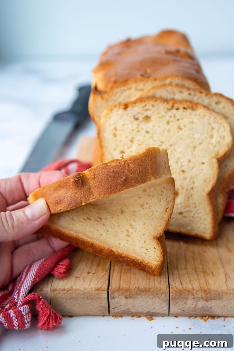 a hand squishing a slice of gluten free bread, demonstrating its remarkable softness