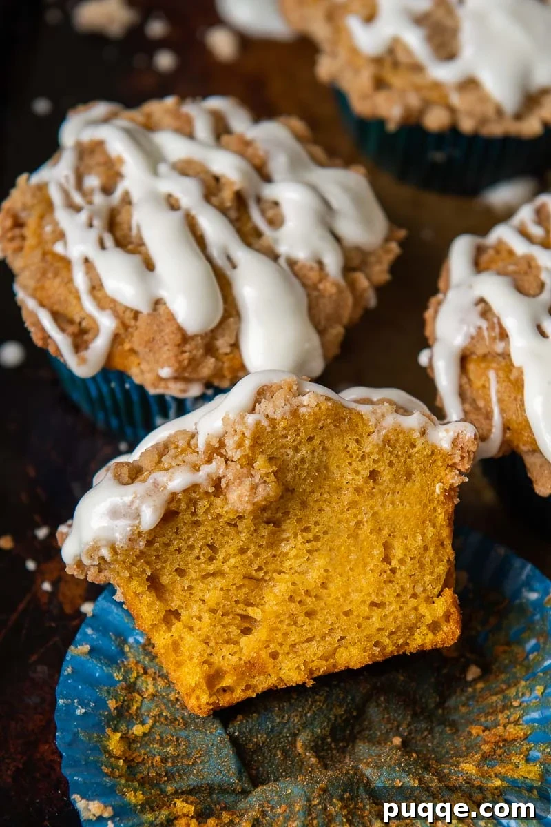Pillowy Gluten-Free Pumpkin Muffins with a Tangy Cream Cheese Glaze 2 A perfectly baked gluten-free pumpkin muffin, split open to reveal its moist interior, resting invitingly on a muffin liner.