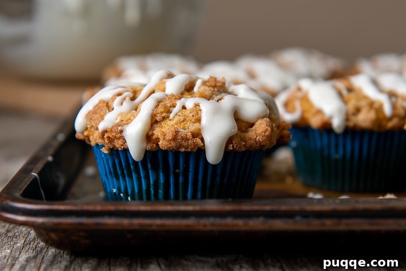 Pillowy Gluten-Free Pumpkin Muffins with a Tangy Cream Cheese Glaze 6 A beautiful, straight-on view of a gluten-free pumpkin muffin, showcasing its golden crumb topping and elegant drizzle of cream cheese glaze.