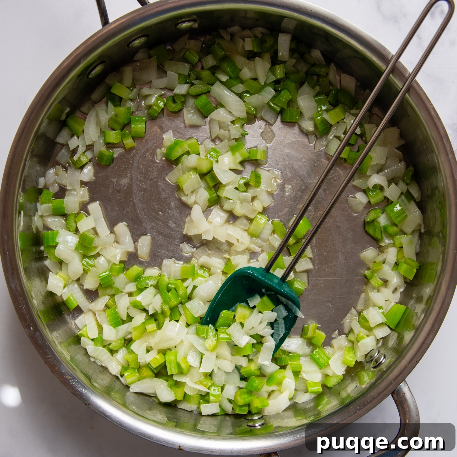 Chopped celery and onion cooking in butter in a sauté pan, forming the aromatic base of the stuffing.