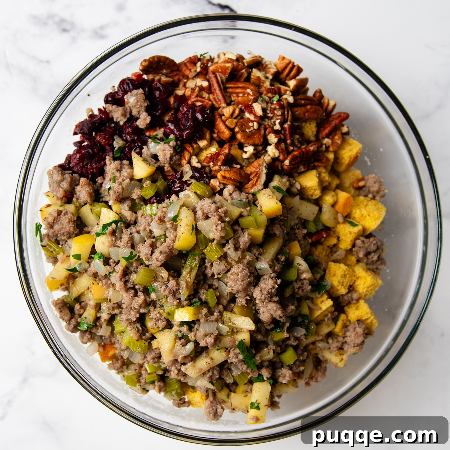 All the delicious gluten-free stuffing ingredients gathered in a large bowl, ready to be mixed.
