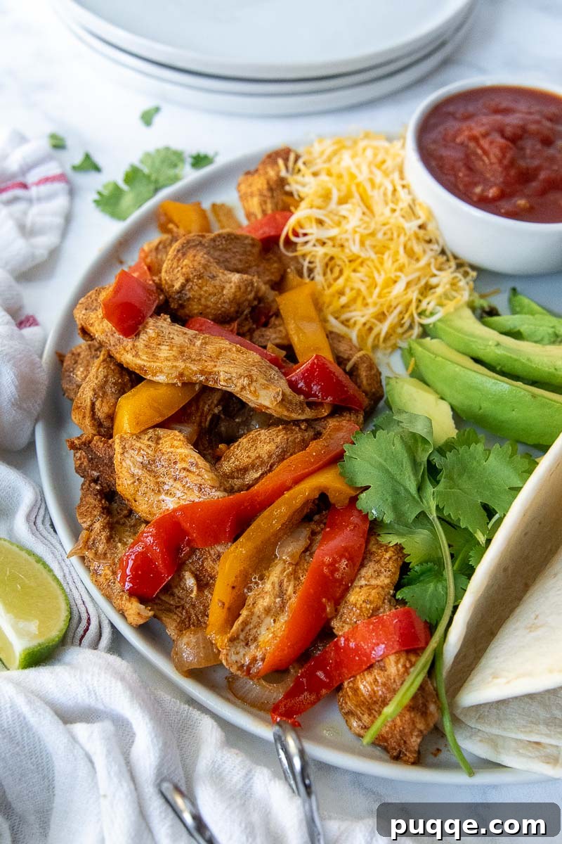 A vibrant plate of Instant Pot chicken fajita meat, colorful peppers, and onions, served alongside a bowl of fresh salsa.