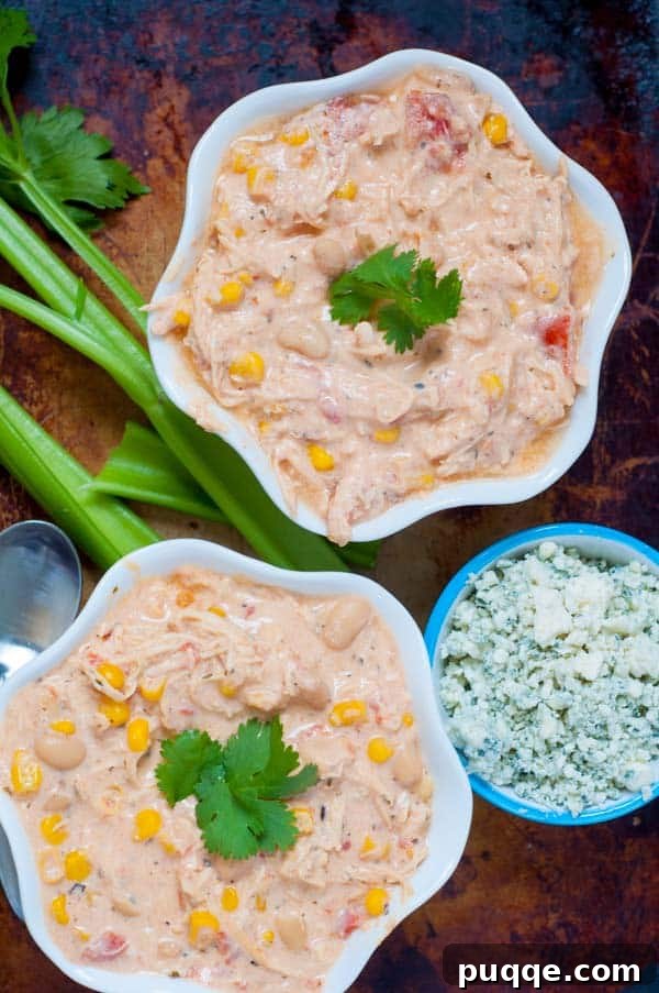 Award Winning Slow Cooker Buffalo Chicken Chili 3 Two vibrant bowls of buffalo chicken chili, artfully arranged with garnishes of crisp celery sticks and crumbled blue cheese, ready to be served.