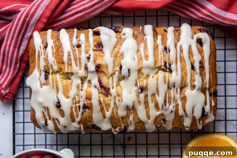 Luscious Gluten-Free Cranberry Buttermilk Loaf 7 Overhead shot of an unsliced Gluten-Free Cranberry Orange Bread loaf on a cooling rack, beautifully drizzled with an orange glaze, ready to be served.