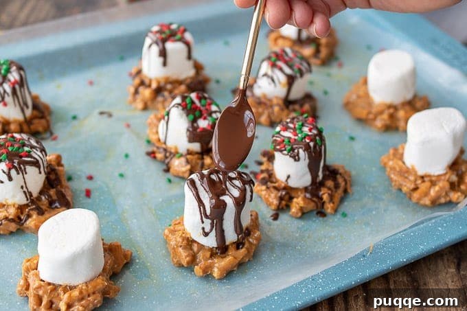 A small spoon delicately drizzling melted chocolate over a homemade Caramel Marshmallow Treat, enhancing its presentation.